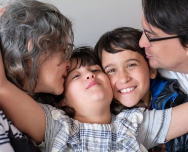 A joyful family of four sharing a warm embrace, highlighting love and togetherness indoors.