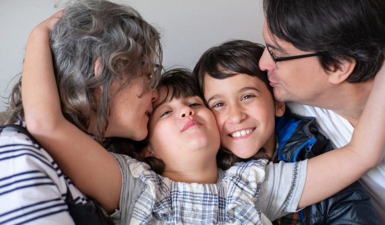 A joyful family of four sharing a warm embrace, highlighting love and togetherness indoors.